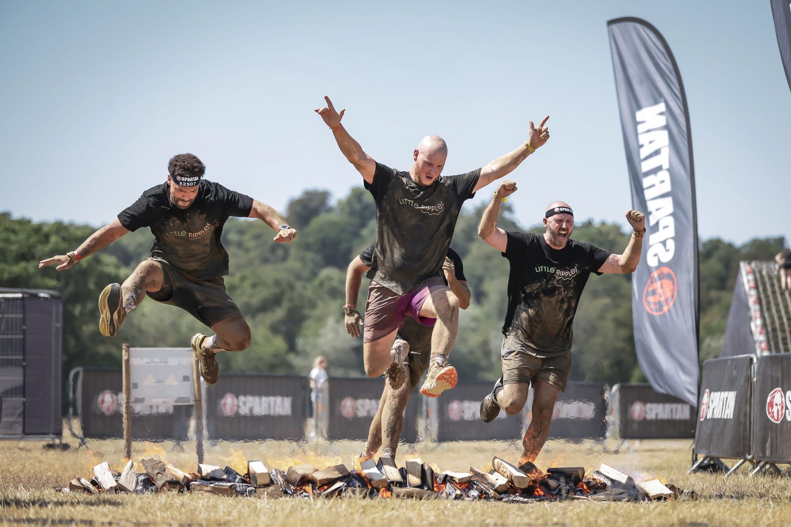 Little Ripples supporters leaping over the fire jump at a Spartan obstacle race