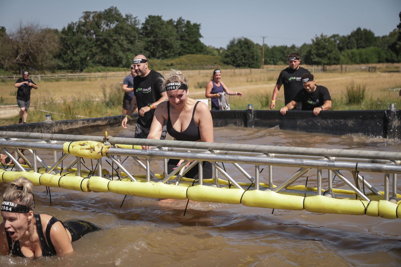 Little Ripples supporters in branded shirts making their way through the water obstacle at a Spartan race